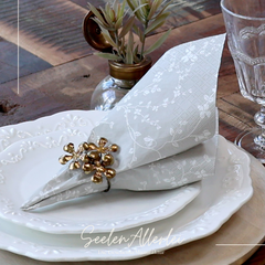 Serviette grau von Chic antique mit einem messingfarbenen Serviettenhalter auf einem gedeckten Teller