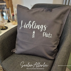 Kissen mit der Aufschrift "Lieblingsplatz" liegt auf einem Stuhl im Ladenlokal