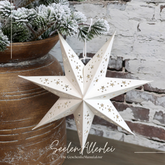 Papierstern in cremeweiß hängt an einem Bäumchen