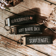 Graue Schlüsselanhänger mit dem aufdruck Glücksbringer - Gott behüte Dich und Schutzengel