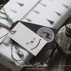 Beispielfoto von 2 Geschenkanhänger, die an ein schön eingepacktes Weihnachtsgeschenk gebunden wurden.