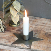 Messing kerzenständer in Sternform mit einer brennenden weißen Kerze steht auf einem Holzregal