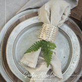 Serviettenring aus Bambus geflecht mit einer Serviette liegt auf einem schön eingedecktem Tisch mit zwei Tellern