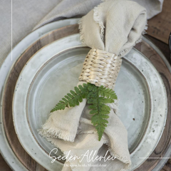 Serviettenring aus Bambus geflecht mit einer Serviette liegt auf einem schön eingedecktem Tisch mit zwei Tellern