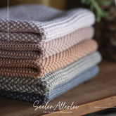 Spültucher der Serie Mynte von IBLaursen liegen gestapelt in verschiedenen Farben auf einem Holzregal