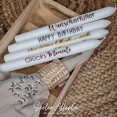 4 Stabkerzen liegen mit unterschiedlichen Sprüchen auf einem Holztablett neben einer Stoffserviette mit serviettenring auf einem passenden Tappich