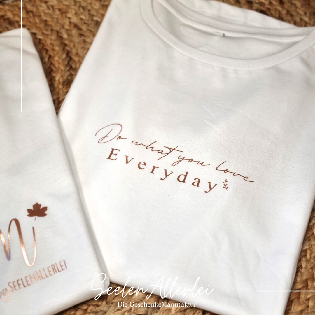 T-shirt mit dem spruch Do what you love everyday aufgedruckt liegt zusammengefaltet auf einem teppich