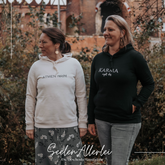 Diana Göckener und Marina Wesseler tragen personalisierte Hoodies mit Sprüchen ATMEN reicht und KARMA regelt das von SeelenAllerlei in Offwhite und Schwarz