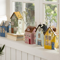 bunte Keramikhäuser als Teelichthalter stehen in einer Reihe wie eine kleine Stadt auf deiner Fensterbank als Designbeispiel