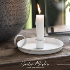 weiße Kammerleuchte auf einer Holzfensterbank mit brennenden Kerze