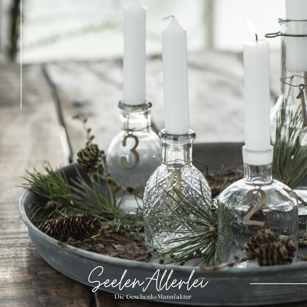 Adventsteller aus Metall, auf dem vier Apothekerflaschen stehen, die für einen Adventskranz mit Zahlen versehen sind.