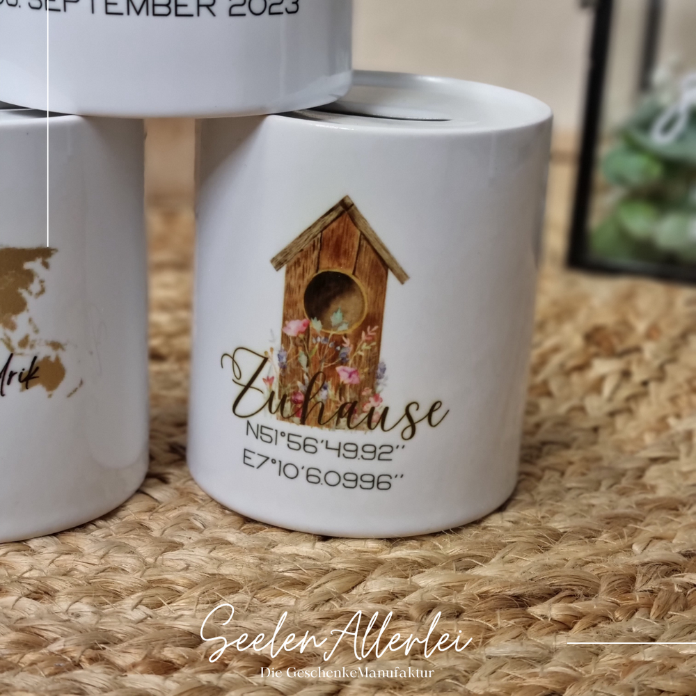Detailaufnahme Spardose zum Einzug mit der Aufschrift Zuhause und den Koordinaten