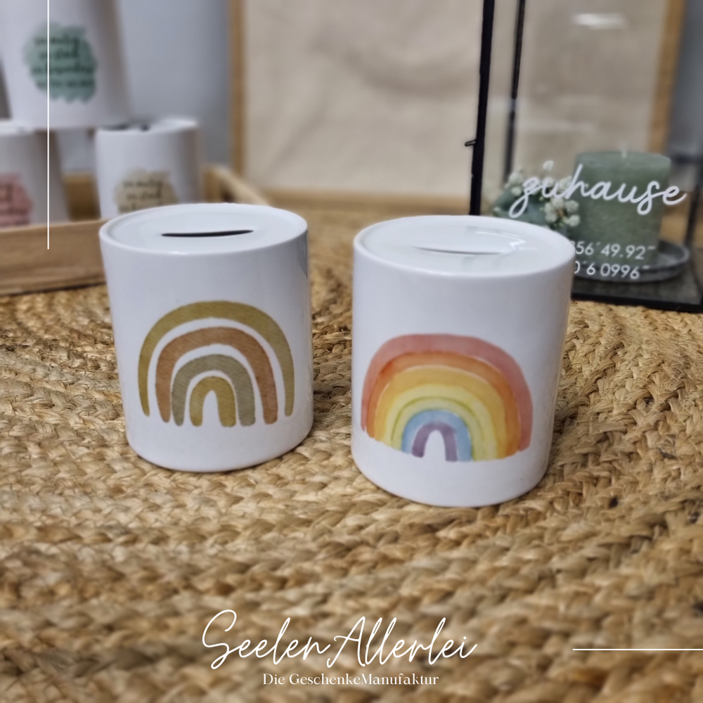 weitere Spardosen mit verschieden farbigen Regenbögen stehen auf dem Teppich vor der Laterne