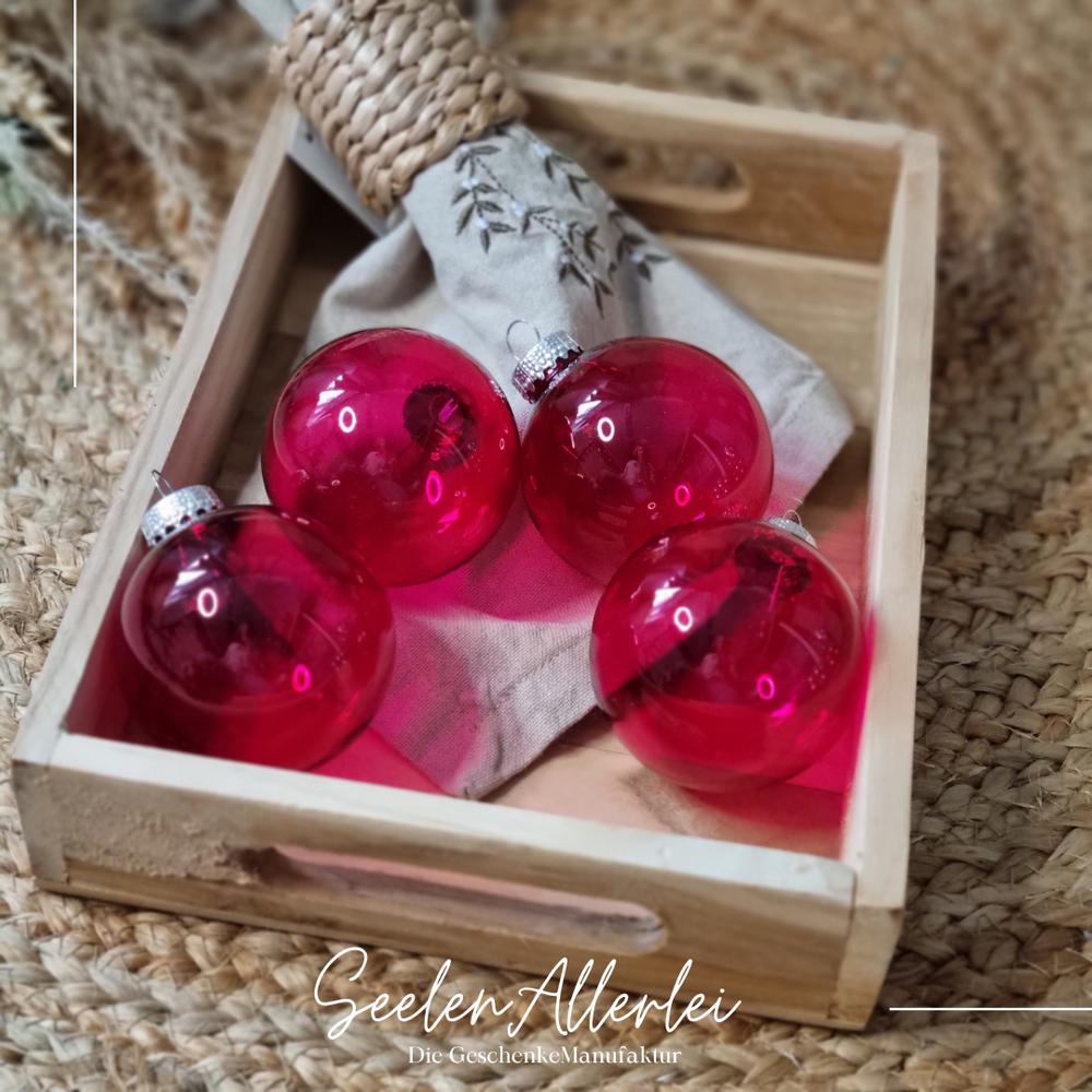 rot pinke durchsichtige Baumkugeln in einer Holzschale