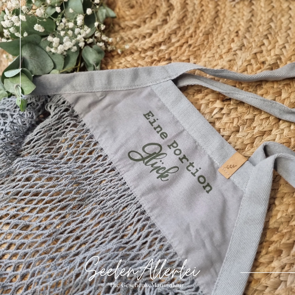 Grauer Netzbeutel von Westfordmill mit der Aufschrift Eine Portion Glück