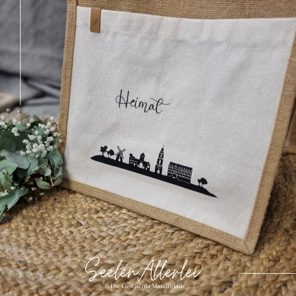 Heimat Coesfeld Silhouette in schwarz auf einer Tasche gedruckt, die auf einem Teppich steht mit Eukalyptusdekoration