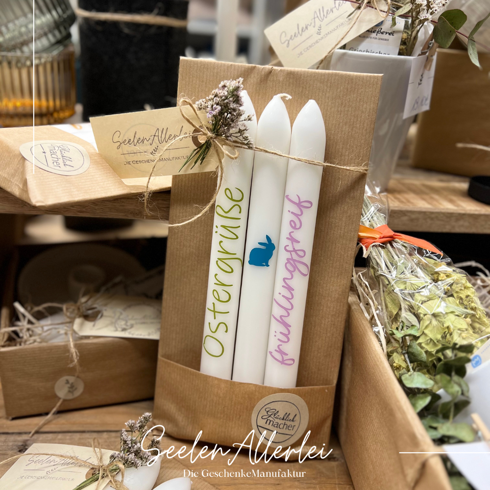 Stabkerzen mit bunter Aufschrift schön verpackt zum Verschenken stehen auf einem Holztisch