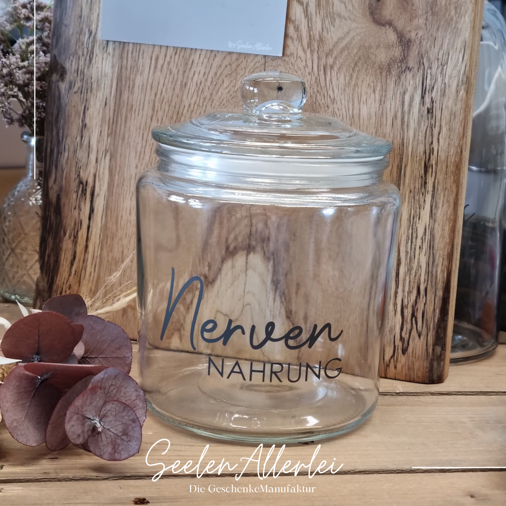 Bonbonglas mit schönem Glasdeckel un der Aufschrift Nervennahrung steht auf einem holztisch