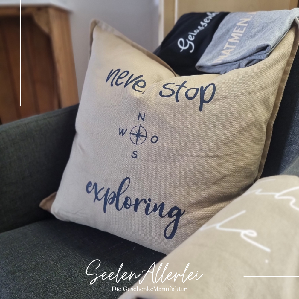 Never Stop exploring mit Kompass liegt auf einem Sessel