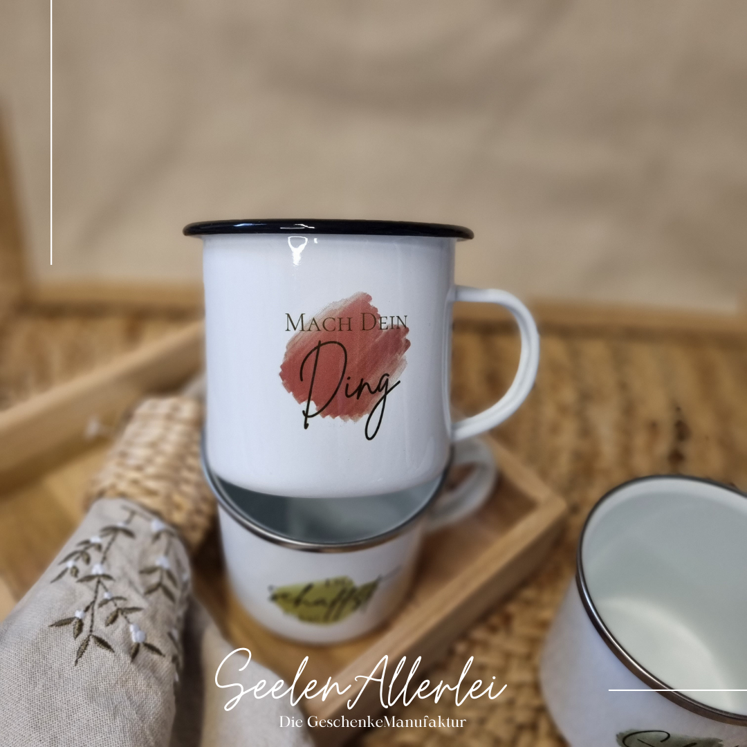 "Mach Dein Ding" auf einem farbigem Hintergrund auf einer Emaille-Tasse mit scharzem Rand