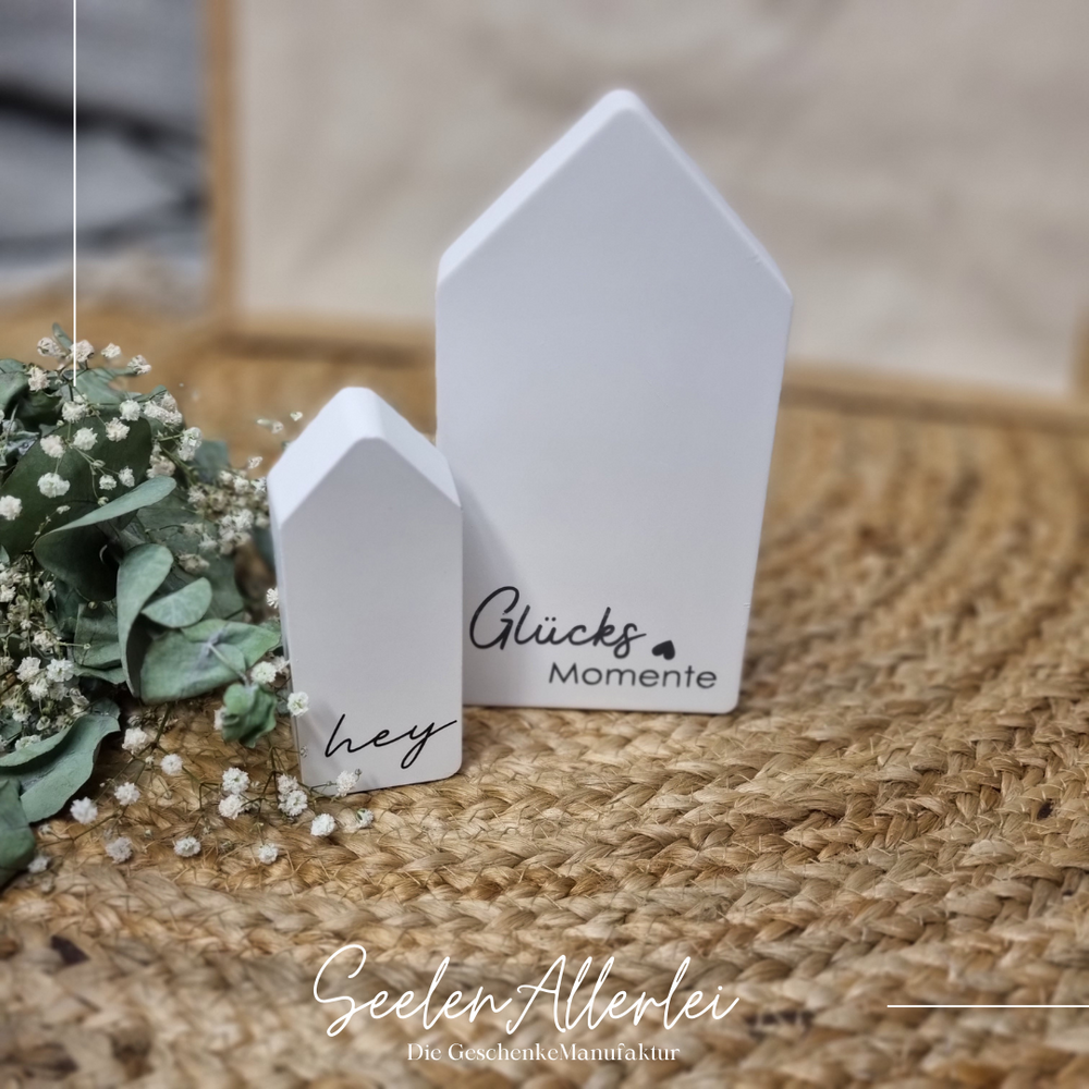 Raysinhäuser in weiß und klein stehend mit der Aufschrift Glücksmomente und hey