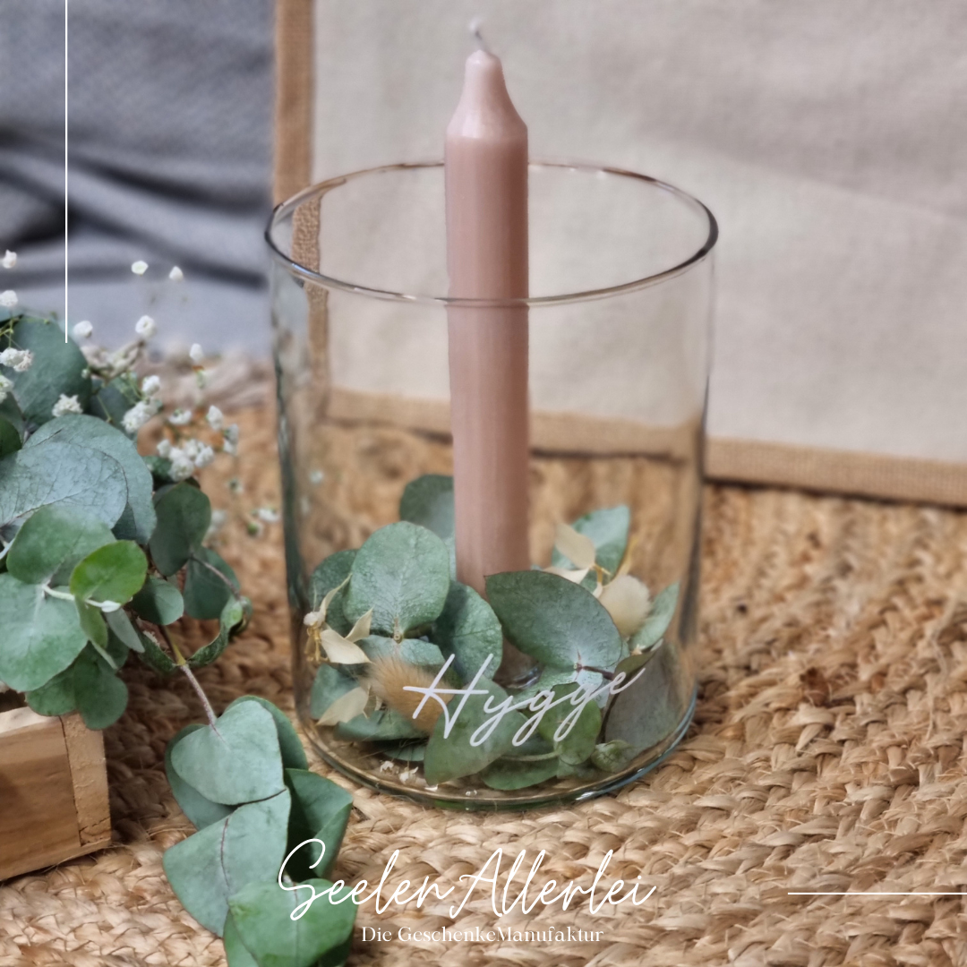 Individualisiertes Kerzenglas hygge mit einer rosafarbener Kerze und Eukalyptusdekoration