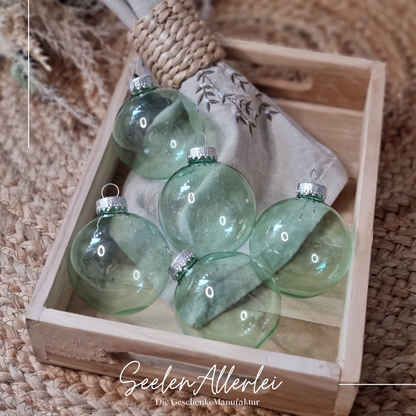 grüne durchsichtige Weihnachtsbaumkugeln aus Glas in einem Tablett