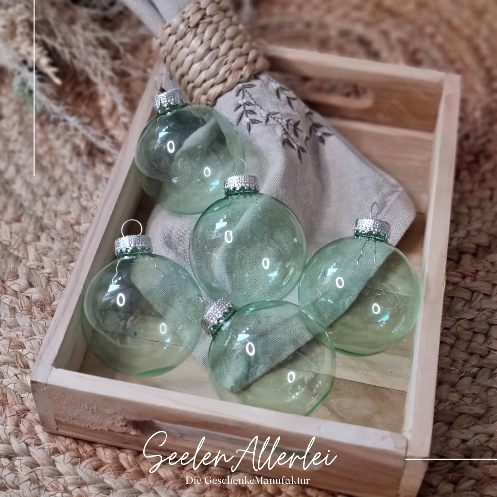 grüne durchsichtige Weihnachtsbaumkugeln aus Glas in einem Tablett