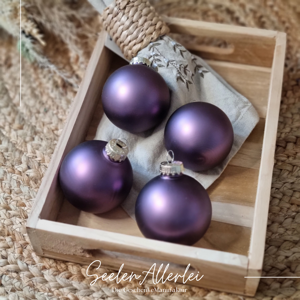 satinierte lilafarbene Baumkugeln für den Tannenbaum liegen  auf einem Holztablett