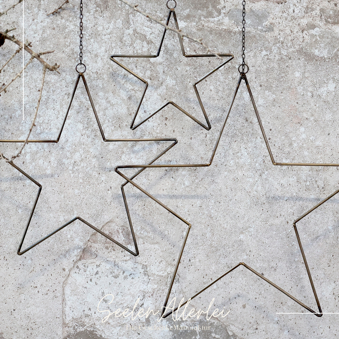 Stern aus Metall zum Hängen in Messingoptik vor einer betonwand zur Dekoration