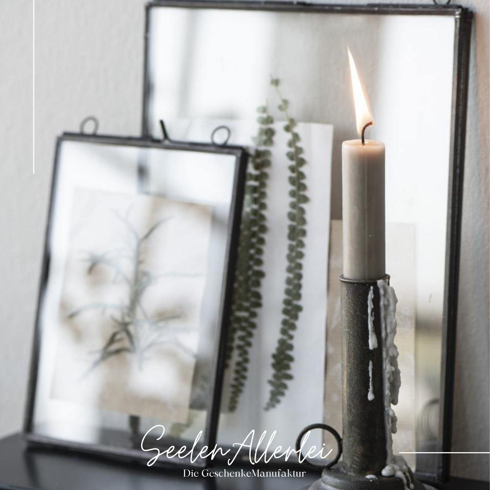 Glasrahmen schwarz mit Kerze im Vordergrund lehnen an der Wand