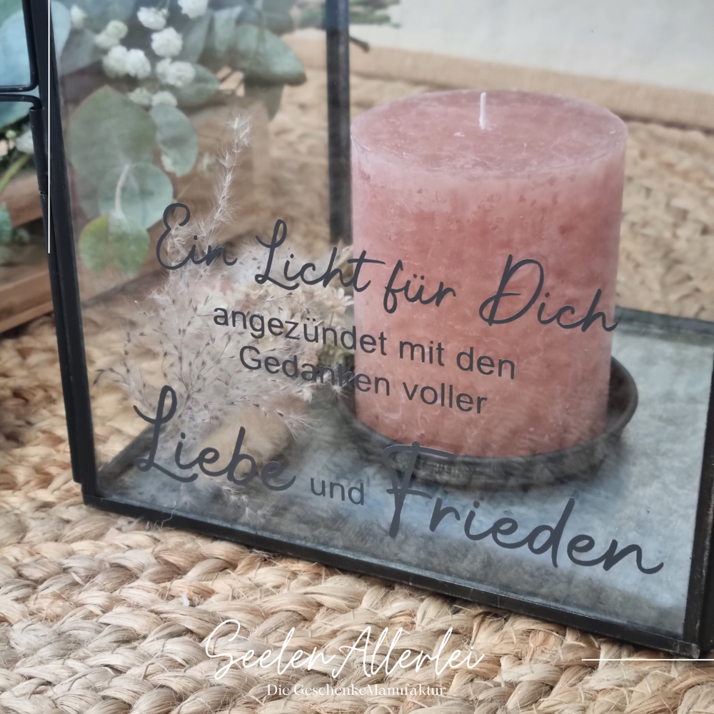 Ein Licht für Dich angezündet mit den Gedanken voller Liebe und Frieden steht auf einer Laterne, die mit einer Kerze dekoriert auf dem Boden steht
