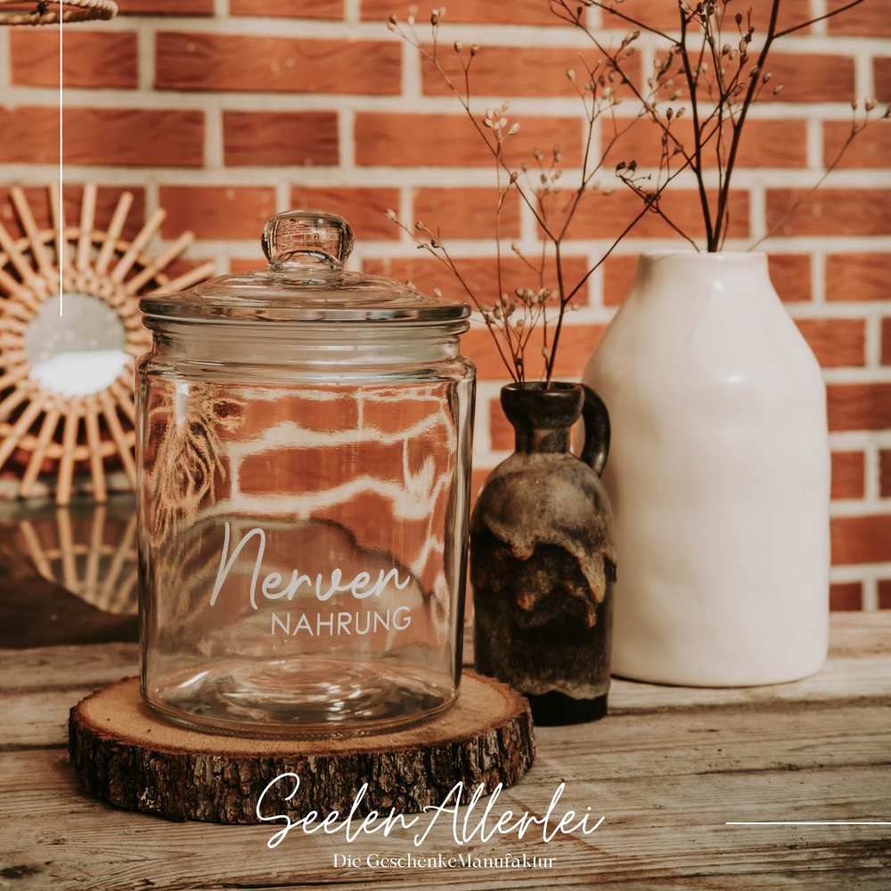 Bonbonglas mit Glasdeckel auf einem Holztisch neben zwei Vasen vor einer Klinkerwand