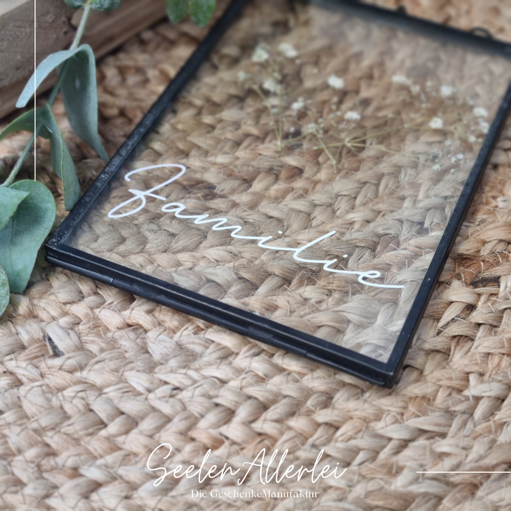 Auf einem Teppich liegt ein schwarzer Glasrahmen mit einer Trockenblumendekoration zur Produktfotografie