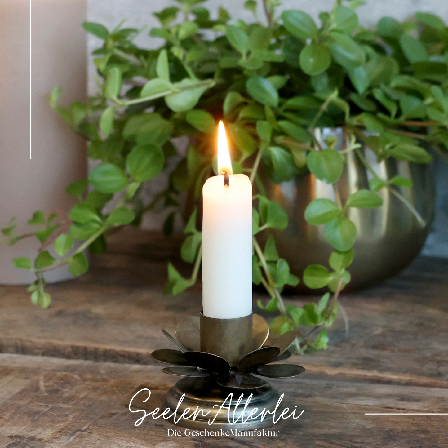 Kerzenhalter aus messing in Form einer Blume mit einer brennenden Kerze.
