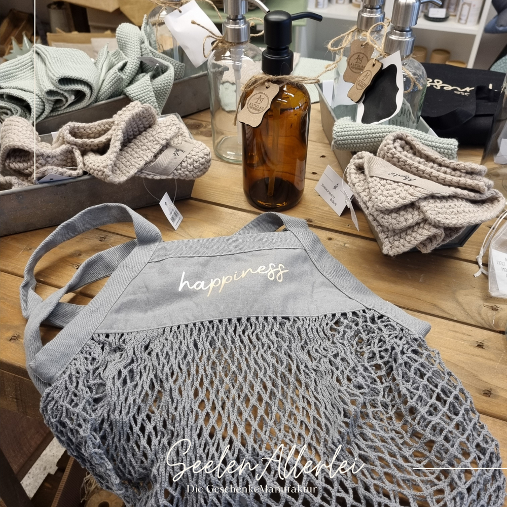 Netzbeutel in grau auf einem Tisch mit Topflappen von IBlaursen und Seifenspendern aus Glas