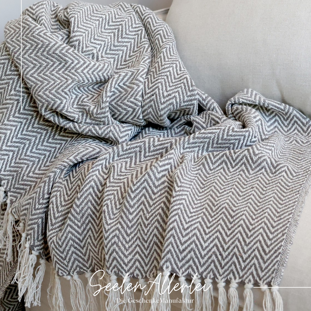 Plaid liegt auf einem hellen Sofa