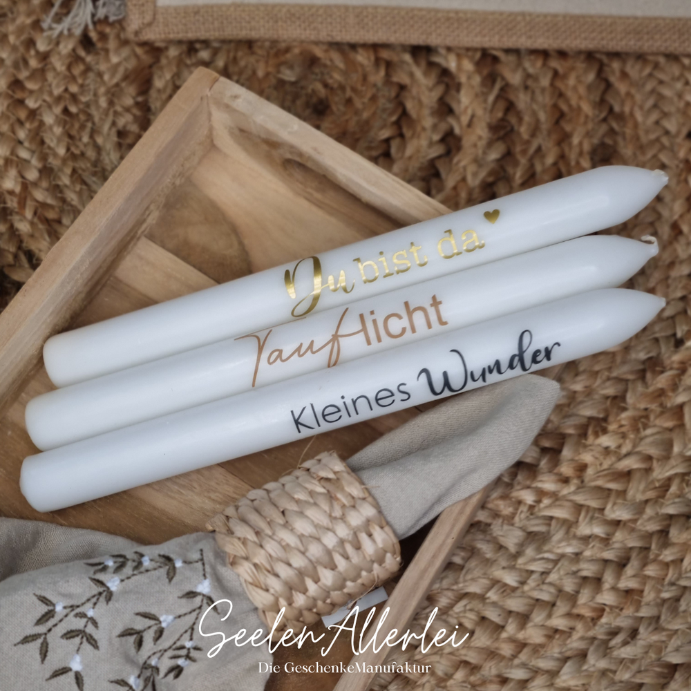 Stabkerzen zur Geburt mit verschiedenen Aufschriften liegen in einer Holzschale