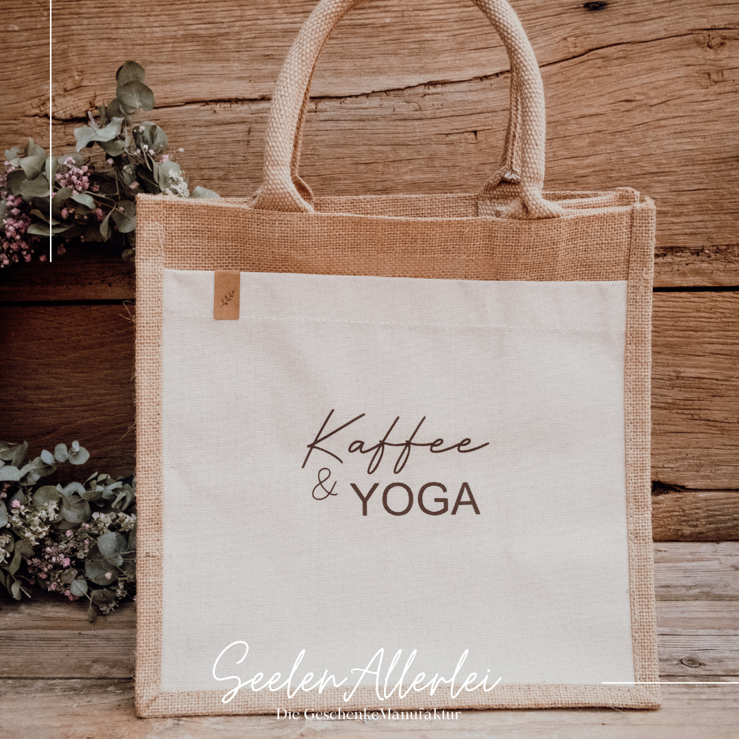 Markttasche mit der Aufschrift Kaffee und Yoga vor einem Holzhintergrund und getrockneten Zweigen zur Dekoration