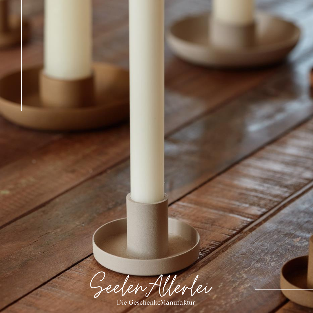 Kerzenhalter in der Farbe ash grey mit dünner Stabkerze auf einem Holztisch.