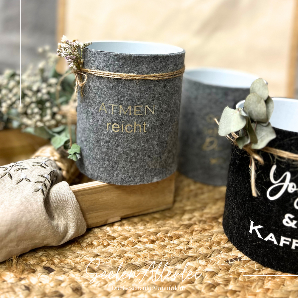 Mehrere Dosen mit Filz und Sprüchen stehen auf einem Teppich zur Auswahl