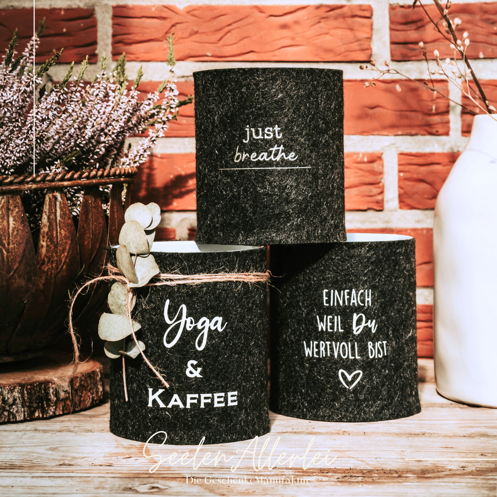 drei Dosen in anthrazit als Aufbewahrung vor einer Mauer auf einem Holzbrett