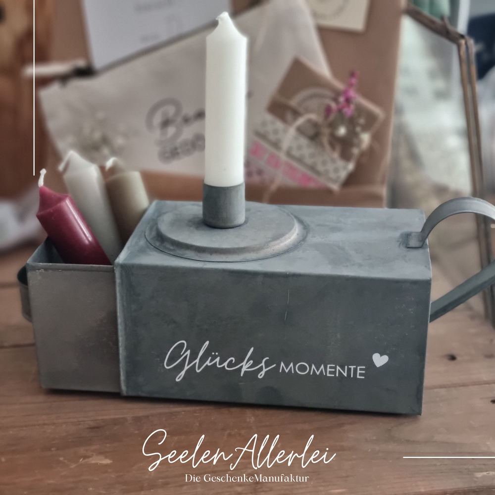 Kerzenbox aus Zink mit der Aufschrift Glücksmomente und verschieden farbigen Kerzen in der Schublade