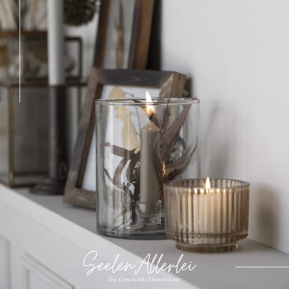 Personalisiertes Kerzenglas mit brennender Kerze in gemütlichem Wohnambiente neben anderen Kerzen