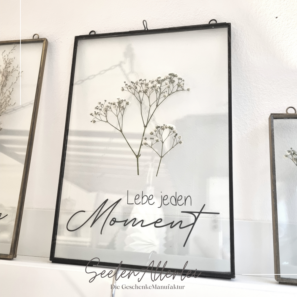 Schwarzer großer Glasrahmen mit einem schwarzen Aufdruck Lebe jeden Moment