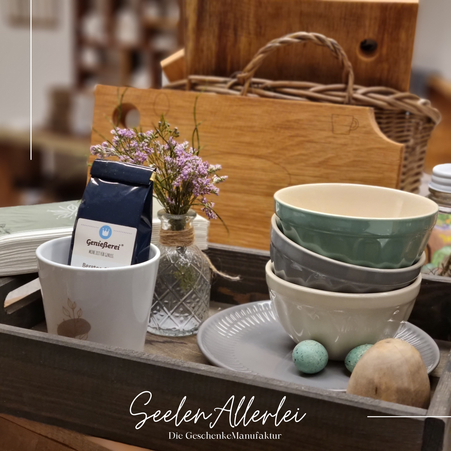 Holztablett mit einem Teller, 3 Schalen in verschiedenen Farben, einer Porzellantasse mit Tee und einem Apothekerglas mit Trockenblumen stehen auf einem Holztisch