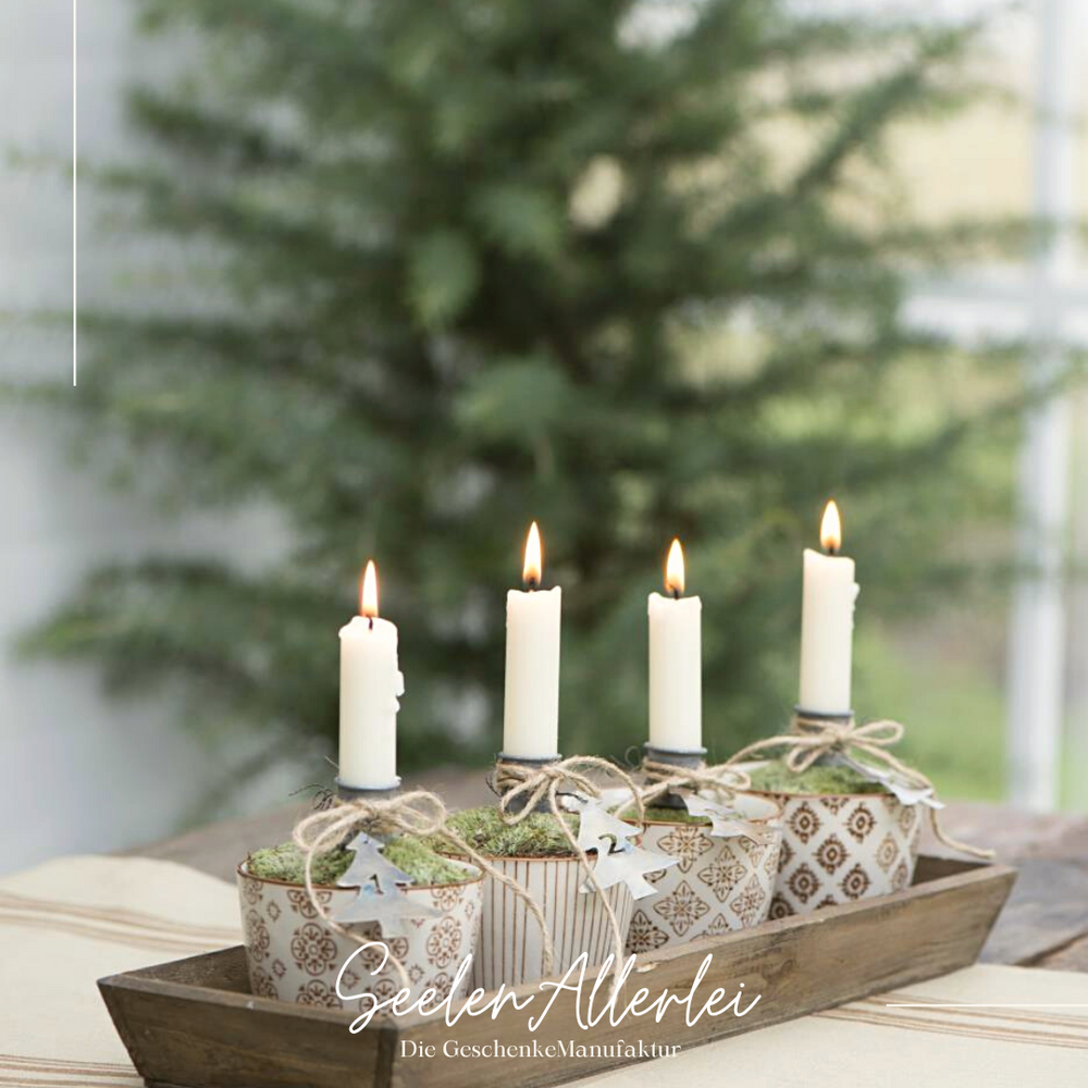 4 tassen mit jeweils einem Kerzenstecker und einer brennenden Kerze als Adventskranz in einer Holzschale